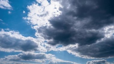 Kümülüs bulutlarının zamanı mavi gökyüzünde ilerliyor. Gri ve yumuşak beyaz bulutların arka planı bulutlu uzayda şekil değiştirir. Zaman atlamalı hava değişikliği. Doğal arka plan, kopyalama alanı. 4K