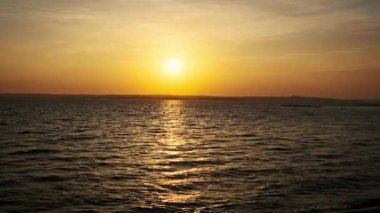Gün batımında su yüzeyinde ağır çekimde. Batan güneşte altın renkli dalgaların güzel arkaplanı. Güneş ışınlarının su yüzeyine yansıması. Dalgaların üzerinde gün batımı. Dalgalar kıyıya vuruyor