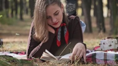 Battaniyenin üzerinde uzanmış ormanda kitap okuyan güzel bir genç kadın. Onun eli nazikçe kitabın sayfalarını çevirir, doğanın güzelliğiyle kusursuz bir şekilde harmanlanır. Doğada dinlenmek. Yavaş Hareket