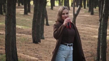 Neşeli genç bir kadın çam ormanında ağır çekimde dönüyor. Güzel kız, doğadaki hayattan zevk alıyor, poz veriyor, mutlu bir şekilde dans ediyor, etrafa bakıyor, hayattan zevk alıyor. Özgürlük havası, romantik. Yaşam biçimi