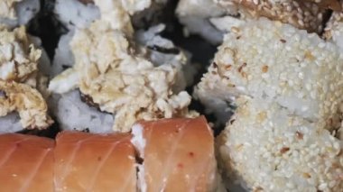 Suşi plastik bir teslimat kutusunda yuvarlanır. Yakın çekim döner. Yemeye hazır suşi kutusu ve farklı lezzetli Japon dürümleri plastik bir kabın içinde dönüyor. Yemek teslimatı, paket yemek..
