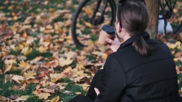 Een Jonge Vrouw Drinkt Koffie Zittend Een Grasveld Een Herfstpark — Stockvideo