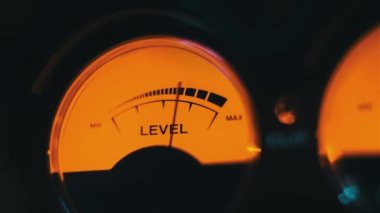 Sarı arka ışıklandırmalı ses sinyali seviyesinin analog yuvarlak ok göstergesi. Klasik retro VU ölçere yakın çekim. Eski ekipman, müzik ya da kayıt. Kayıt cihazındaki ses dB desibelleri