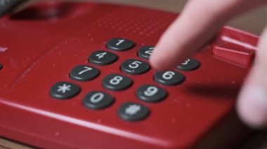 911 'i arıyorum. Eski bir kırmızı telefonda, erkek eli çevirme tuşlarına basar. Eski bir ev telefonundan acil durum numarasını arıyorum. Retro tuşlu numara tuşları. Yakın plan.