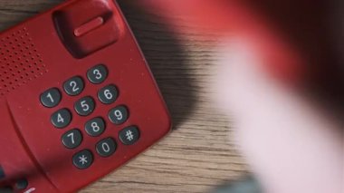 911 'i arıyorum. Eski bir kırmızı telefonun üst görüntüsü, erkek eli tuşlara basar. Eski bir ev telefonundan acil durum numarasını arıyorum. Retro tuşlu numara tuşları. Yakın plan.