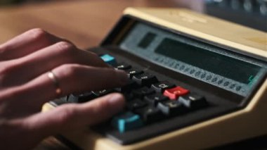 Tahta masadaki eski bir hesaplama makinesinin erkek eli tuşlarına basar. Vintage hesap makinesine güvenerek. Konsept ev finansmanı, para birimi, tasarruf, finans faturaları, bütçe