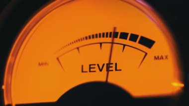 Sarı arka ışıklandırmalı ses sinyali seviyesinin klasik analog ok göstergesi. Analog VU ölçere yakın çekim. Retro ekipman, müzik çalma ya da kayıt. Ses düzeyi ile ses düzeyi senkronize ediliyor