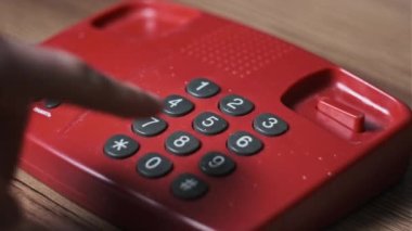 911 'i arıyorum. Eski bir kırmızı telefonda, bir adam tuşlara basar. Eski bir ev telefonundan acil durum numarasını arıyorum. Retro tuşlu numara tuşları. Yakın plan.