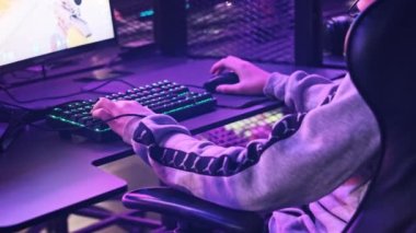 Esport kulübündeki genç bir çocuk oyun sandalyesinde monitörün önünde oturup atış oyunu oynuyor. Bilgisayar kulübünde kulaklık takan bir genç bir video oyununa odaklanıyor, arkadaşlar çevrimiçi turnuva oynuyor