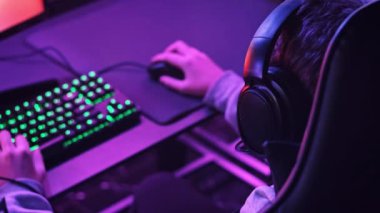 Genç oyuncu profesyonel bir oyun koltuğunda oturur ve E-spor kulübünde video oyunları oynar. Kulaklıklı bir çocuk bilgisayar kulübünde neon ışıkları olan bir video oyununa odaklanıyor. Oyun kulübünde genç, hobi olarak.