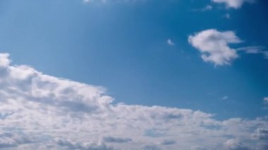 Kümülüs bulutlarının zamanı mavi gökyüzünde ilerliyor. Işık ve ağır sakin bulutların arka planı bulutlu uzayda şekil değiştirir. Doğal arka plan, hızlandırılmış zaman, kopyalama alanı. 4K.
