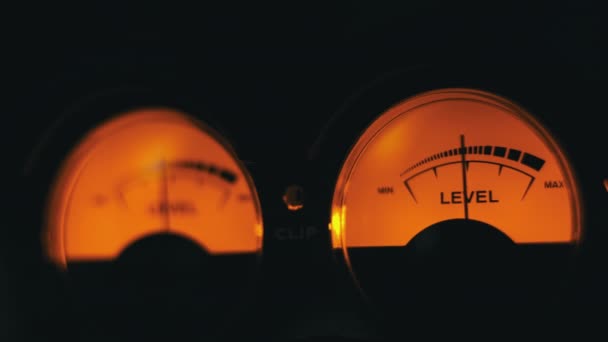 オーディオ信号レベルの2つのアナログダイヤルインジケータ ヴィンテージの矢印は サウンドレベルと同期して移動します 黄色のバックライト Vuメートルとラウンド古典的なボリュームスケール 古いゲージ測定Dbデシベルのクローズアップ — ストック動画