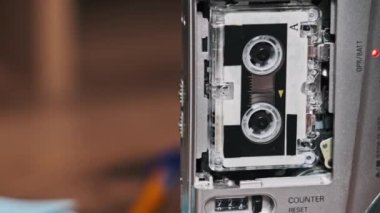 Klasik mikro kaset kaydedici ayakta dikiliyor. Mikro kasetin yakın çekimi ve ahşap bir masanın üzerindeki kayıt cihazındaki rulo kaset. Kayıt, kayıt sesi, diktafon