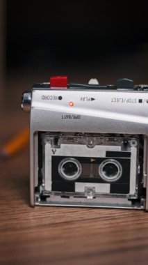 Dikey Mikrokaset Tahta Masa üzerinde taşınabilir bir kayıt cihazında dönüyor. Kullanışlı bant retro çalar. Boş etiketle çalınan portatif eski kaset yakın plan. Mikro kaset. Kayıt sesi