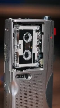 Dikey Mikrokaset Tahta Masa üzerinde taşınabilir bir kayıt cihazında dönüyor. Kullanışlı bant retro çalar. Boş etiketle çalınan portatif eski kaset yakın plan. Mikro kaset. Kayıt sesi