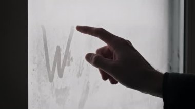 Yazıtlara göre, kar yağışı sırasında parmakları sisli bir camda. Erkek parmağı, kar fırtınası sırasında sisli bir camda Kış kelimesini çizer. El yazısı kelime, mesaj. Kış havası