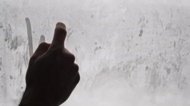 Kelime Kış çizimi, bulanık karla kaplı arka planda cam buğulama penceresinde bir erkek parmağıyla. Kar yağarken sisli bir pencereye yazılmış el yazması bir yazı. Kış havası, metin.