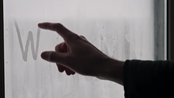 雪の間 窓に指を付けた冬の碑文 男性の指は 雪の嵐の冬の日に霧のガラスに冬という言葉を描いています 手書きの単語 テキスト ウィンターシームード — ストック動画