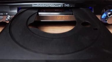 DVD sıkıştırma diski oynatıcıya eklenir. Erkek eli CD 'yi CD çalar tepsisine yakın çekime koyar. Müzik, filmler ya da veriler bir lazer optik bilgi depolama aracına kaydedildi. Küçük Disk Yükleniyor