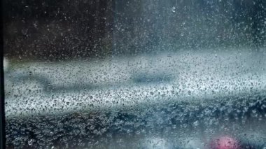 Yağmurlu bir günde yağmur damlalarının arkaplanı pencerenin camından yavaşça aşağı akar, Timelapse. Bir yağmur damlası deseni, yakın plan. Boşluğu kopyala, metin arkaplanı.