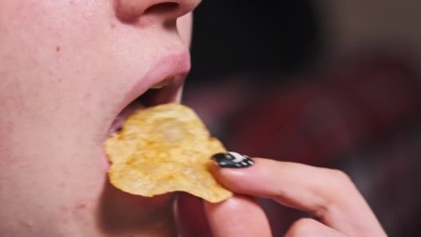 年轻女子嘴上吃着薯片 动作缓慢 雌性的手把脆薯片放进嘴里咀嚼 吃不健康的食物 不健康的饮食 — 图库视频影像