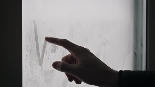 雪の中の霧の窓に指の言葉の冬を描く 男性の指は 雪の嵐の間 冬の日に誤ったガラスに刻印された冬を描きます 手書きのテキスト ウィンターシームード — ストック動画