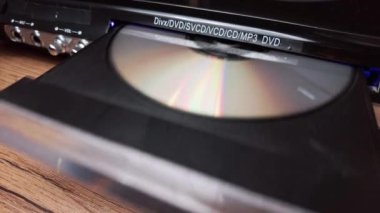 DVD CD oynatıcıdan CD CD indiriliyor. Erkek CD çalar tepsisinden CD 'yi yakın plan çeker. Müzik, filmler ya da veriler bir lazer optik bilgi depolama aracına kaydedildi. Kompakt Disk Çıkılıyor