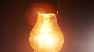 Kablo akkor ampulün üzerinde asılı durmak siyah arka planda yanıp sönen ışıklar açar, metin için yer açar. Isınan filament yakın plan. Cam gibi parlak sarı bir ampul. Tungsten lambası. Fikir 4K