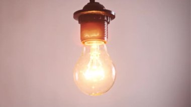 Yanan ampuller açılıp kapanıyor ve beyaz arka planda titreşiyor, yazı için bir yer. Isınan filament yakın plan. Cam gibi parlak sarı bir ampul. Tungsten lamba ışığı. Fikir: Boşluğu kopyala