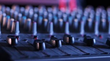 Erkek el faders yukarı ve aşağı ayarlama Neon ışık yakın çekim ses karıştırıcı. Renkli arka planda karıştırma konsolu çalışıyor. DJ çok renkli bir efekt ile müzik çalar. Ses mühendisi düğme seviyesini değiştiriyor