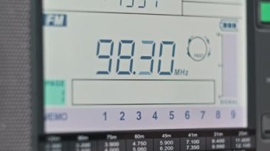 Modern Taşınabilir Radyonun Dijital LCD Ölçeklendirmesinde FM Frekansını Kapat. Çevirme paneli değişik radyo frekanslarıyla büyük rakamları gösteriyor. Taşınabilir radyo otomatik arama menzili. Akort alıcısı