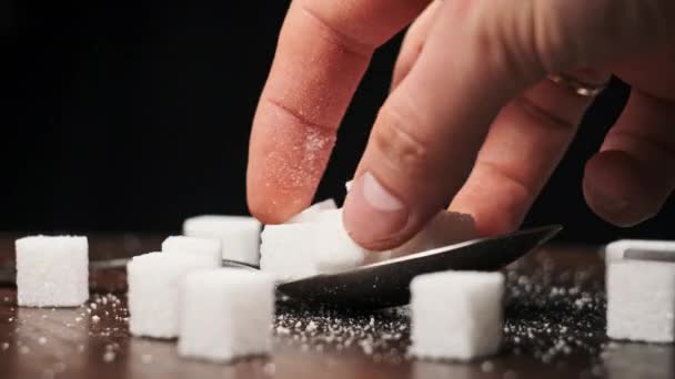 スプーン内の砂糖キューブは テーブルのクローズアップで滑らかな回転です 手は甘い白砂糖のヒープをスプーンに入れる 砂糖中毒 不健康な食事 過体重 糖尿病 肥満を概念する — ストック動画