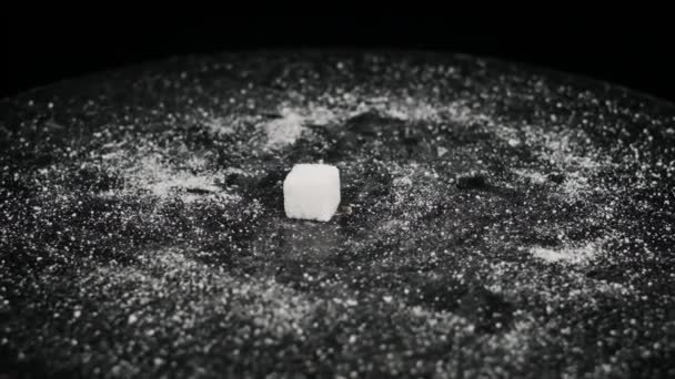 シュガーキューブは回転テーブルの上に落ちてゆっくりと動きます 白い精製された砂糖の硬い部分は黒いテーブルに落ちます 砂糖中毒 不健康な食事 太りすぎ 糖尿病 コピースペース — ストック動画