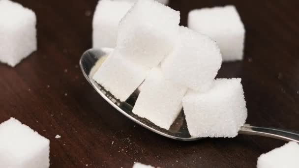 スプーン内の砂糖キューブは テーブルのクローズアップで滑らかな回転です 甘い白砂糖のヒープが付いている金属スプーン 砂糖中毒 不健康な食事 過体重 糖尿病 肥満を概念する — ストック動画
