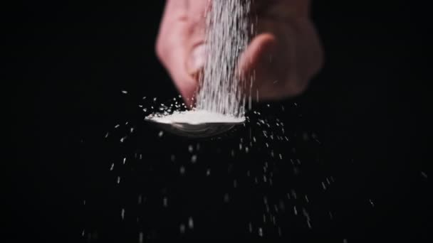 砂糖は黒い背景のスローモーション クローズアップにスプーンに入ります スペースをコピーする 1杯の白砂糖を測定する 砂糖中毒 不健康な食事 太りすぎ 糖尿病 4Kについて — ストック動画