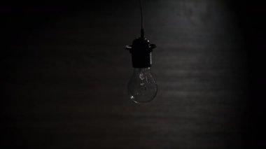 Yanan ampul açılıp kapanıyor ve siyah arkaplanda yanıp sönüyor. Metnin yeri. Isınan filament yakın plan. Cam gibi parlak sarı bir ampul. Tungsten lamba ışığı. Fikir: Boşluğu kopyala