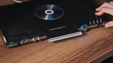 Küçük disk DVD oynatıcıya eklenir. Erkek eli CD 'yi CD çalar tepsisine yakın çekime koyar. Müzik, filmler ya da veriler bir lazer optik bilgi depolama aracına kaydedildi. Küçük Disk Yükleniyor