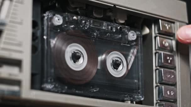 オーディオテープレコーダーの再生 ヴィンテージ透明なオーディオカセットをクローズアップして挿入します 古いテープを再生するレコードプレーヤー レトロテープリールはデッキで回転します アーカイブ 80年代を再生する — ストック動画