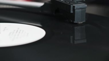 Vinil plak vintage turntable 'da dönüyor, iğne plağa değiyor. El, vinil plağı açar. Stylus yakın plan kayıtlardan yükseliyor. Vinil plak çeviriyorum. Retro müzik çalınıyor