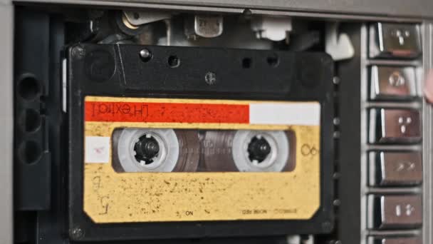 オーディオテープレコーダーの再生 ヴィンテージイエローオーディオカセットをクローズアップして挿入します 古いテープを再生するレコードプレーヤー レトロテープリールはデッキで回転します アーカイブ 80S 4Kのレコーディング — ストック動画