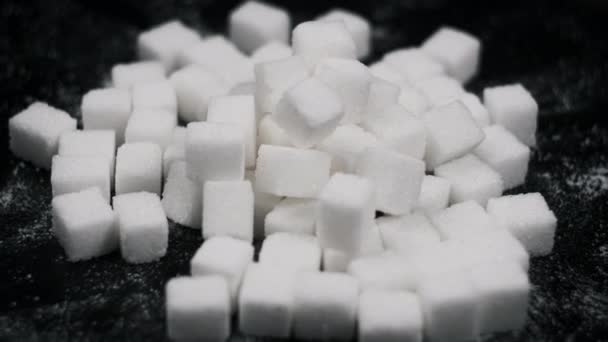 许多糖块在黑色背景的特写下旋转 桌子上旋转着精炼的白色糖块 糖瘾的概念 不健康的饮食 糖尿病 复制空间4K — 图库视频影像
