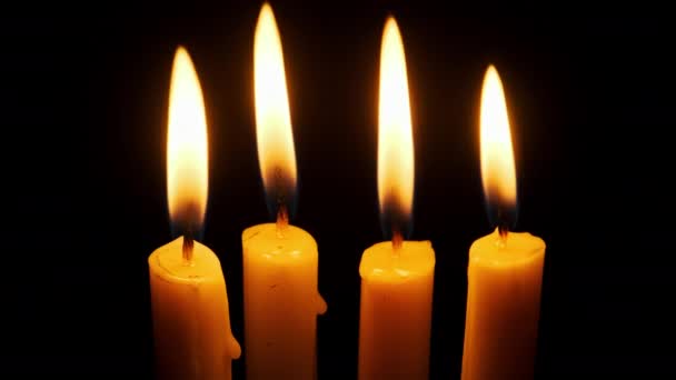 四支蜡烛在黑色的背景上燃烧和熄灭 复制空间 蜡烛的火焰点燃了特写 炽热的烛焰 孤立无援概念纪念 记忆等 — 图库视频影像