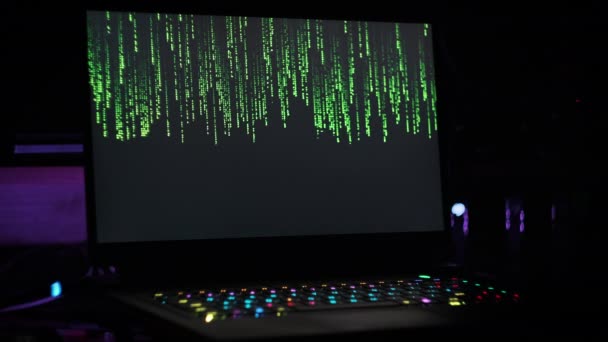 어두운 현대적인 방에서 노트북 화면에 매트릭스 떨어지는 숫자의 배경입니다 바이너리 — 비디오