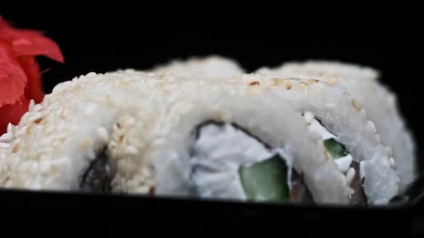 寿司卷在塑料送货箱内旋转特写 即食寿司盒与新鲜的不同烘焙美味的日本卷在塑料容器中旋转 食物运送概念 外卖食物 — 图库视频影像