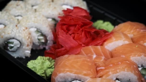 寿司卷在塑料送货箱内旋转特写 寿司盒与新鲜的不同的日本卷 生姜和芥末纺成一个塑料容器 食物运送概念 外卖食物 — 图库视频影像