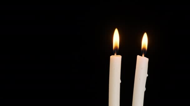 两支蜡烛在黑色的背景上燃烧和熄灭 复制空间 蜡烛的火焰点燃了特写 炽热的烛焰 孤立无援概念纪念 记忆等 — 图库视频影像