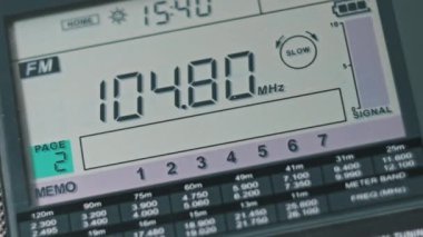 Modern Taşınabilir Radyonun Dijital LCD Ölçeklendirmesinde FM Frekansını Kapat. Çevirme paneli değişik radyo frekanslarıyla büyük rakamları gösteriyor. Taşınabilir radyo otomatik arama menzili. Akort alıcısı