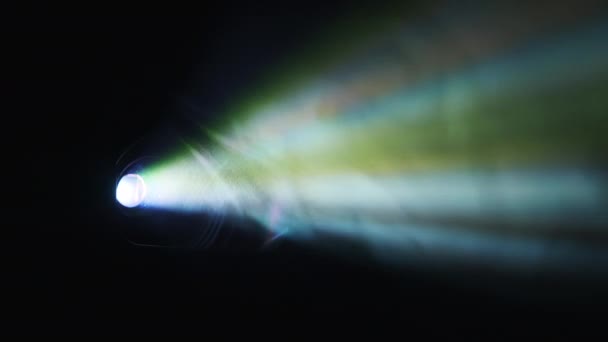 カラフルな煙の点滅ライトが付いているフィルム プロジェクター Searchlightは明るい色のビームを提供しています カラーレイで映画を披露しています レインボーライト ホームシアター スクリーンで画像を送信 — ストック動画