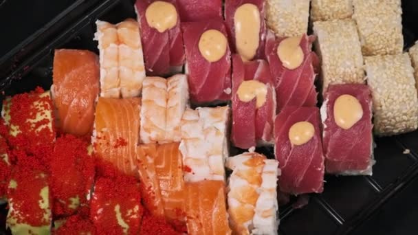 被分类的寿司在一个旋转的送货箱里滚动 背景是黑色的 即食日本人在集装箱内翻滚特写 美味佳肴和外卖服务 — 图库视频影像