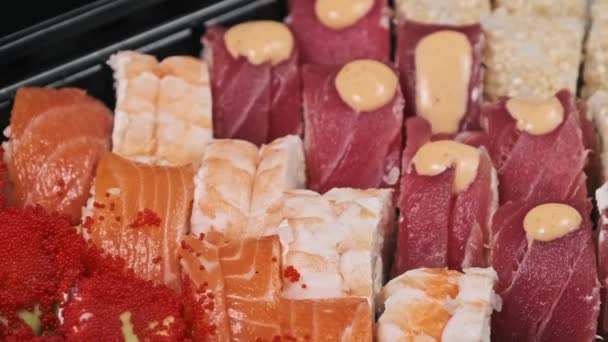 プラスチックのデリバリーボックス内の寿司ロールは クローズアップを回転させます 新鮮な日本のロール わさびをプラスチック容器に回転させた寿司ボックス 食品の配達 持ち帰りの食品の概念 — ストック動画